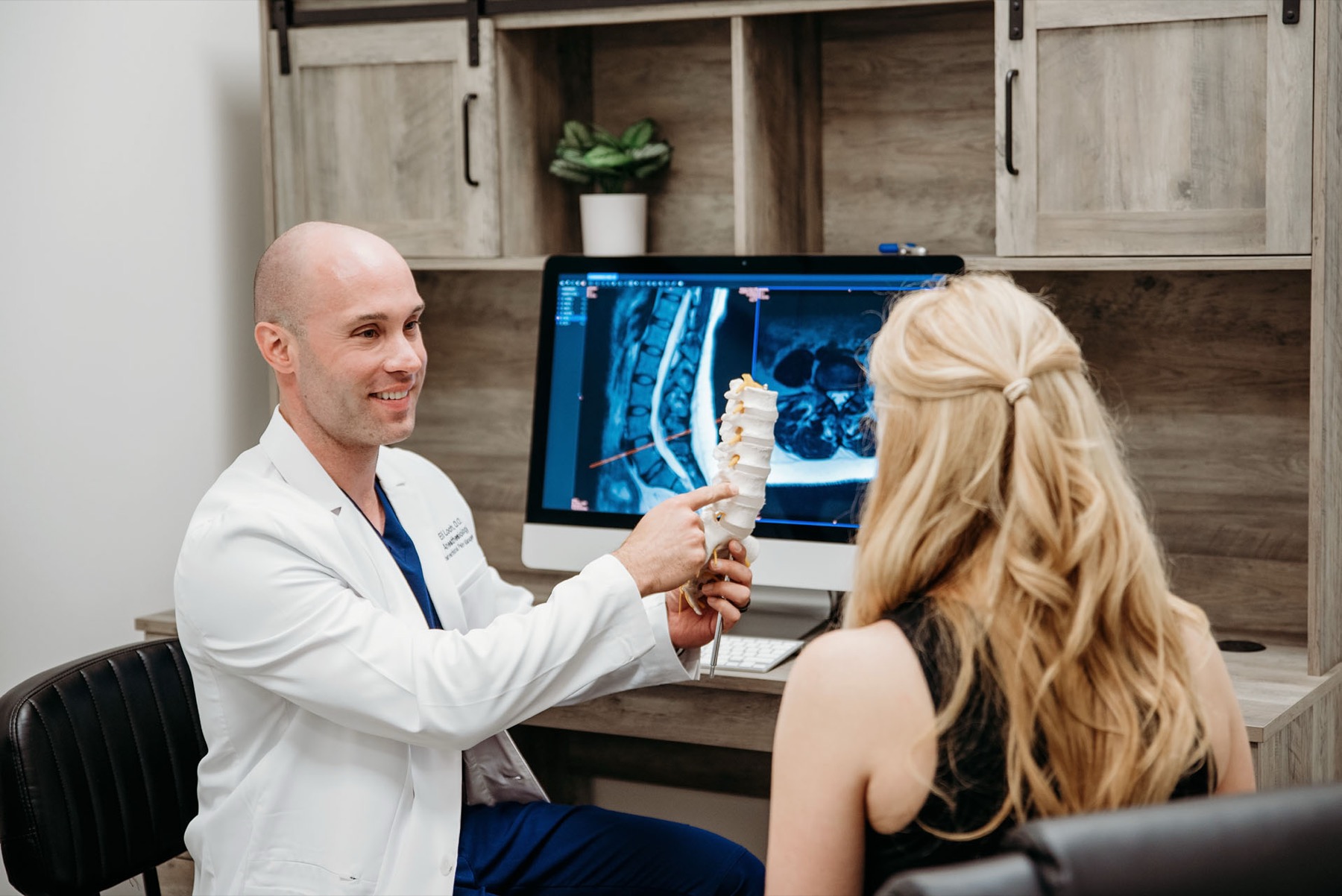 Dr. Loch explaining a spine model and MRI images to a patient